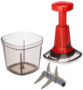 Red color push chopper with it's container and stainless steel chopping board on white board