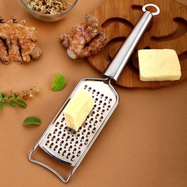 Stainless steel cheese grater on table with cheese