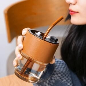 girl sipping beverage in leather grip mason jar