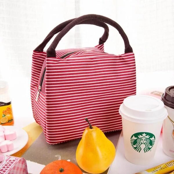 Red color strap design lunch bag on table with fruits and cup