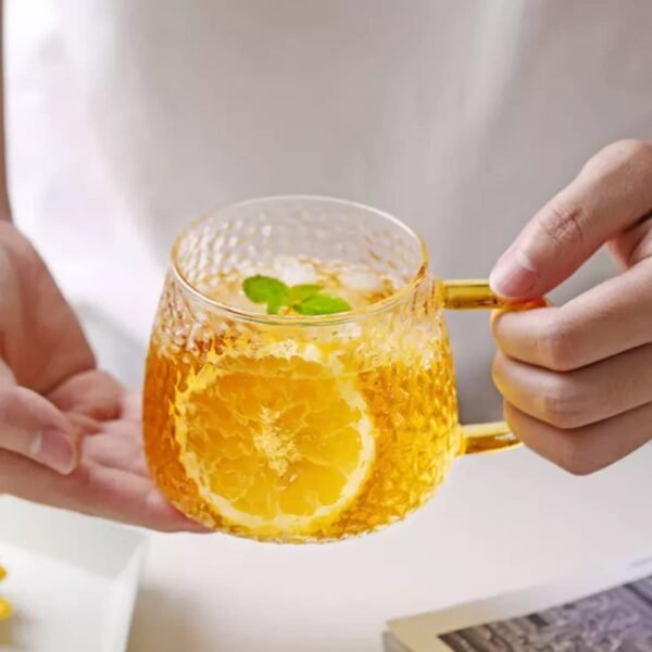 golden handle glass coffee mug filled with lemon tea in hand