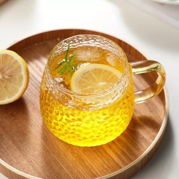 Golden handle glass coffee mug on plate filled with lemon tea