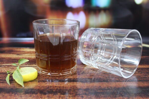 Italian premium glass whiskey glasses set on decorative background with lemon slice filled with beverage