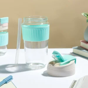 Blue color glass tumbler with dual flip lid and straw on decorative background