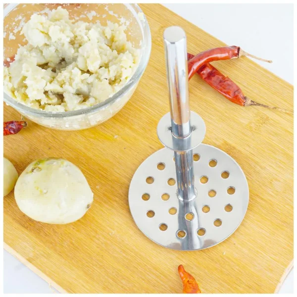 Potato masher on chopping board with mashed potatos