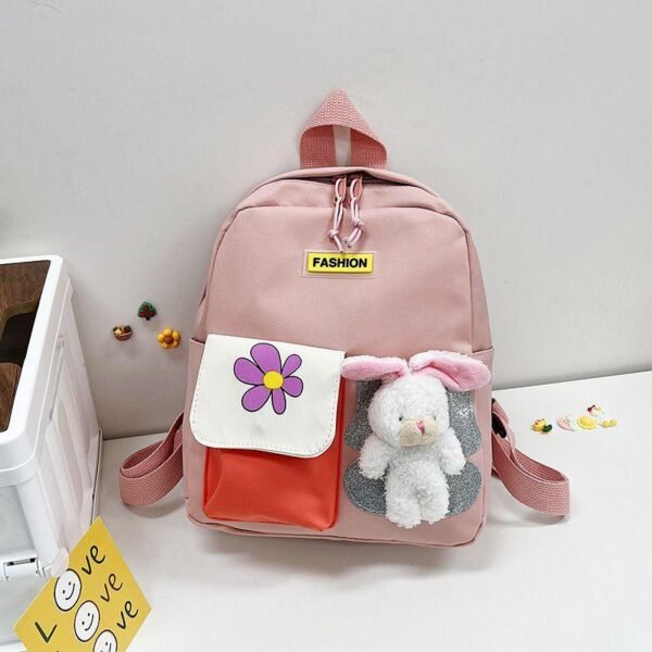 Pink color school bag rabbit toy sticks on it on decorative background