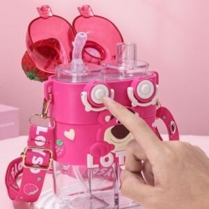 Close up of pink water bottle with a strawberry and Lotso Character on top. A hand pressing the button to open the straw. It has a shoulder strap. Dual functional straw and open mouth for easy sipping.