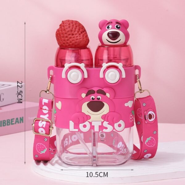 A close up of pink plastic water bottle featuring a strawberry and Lotso character on the top. It has a shoulder strap and two straws, with the words "Lotso" printed on it. Also showing the base length 10.5CM and Height of sipper 22.5CM. Image on table with two books on it.