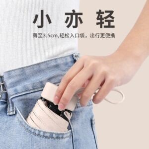 Ultra-compact folding umbrella being placed into a jeans pocket, demonstrating its small size and portability.
