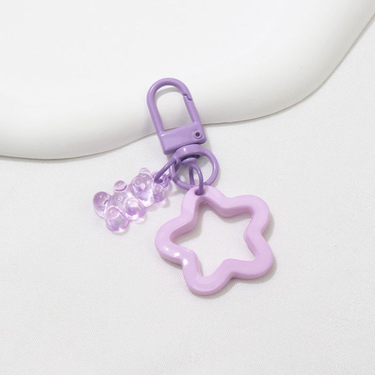 Pastel purple flower and gummy bear keychain on white background. Cute resin keyring accessory.