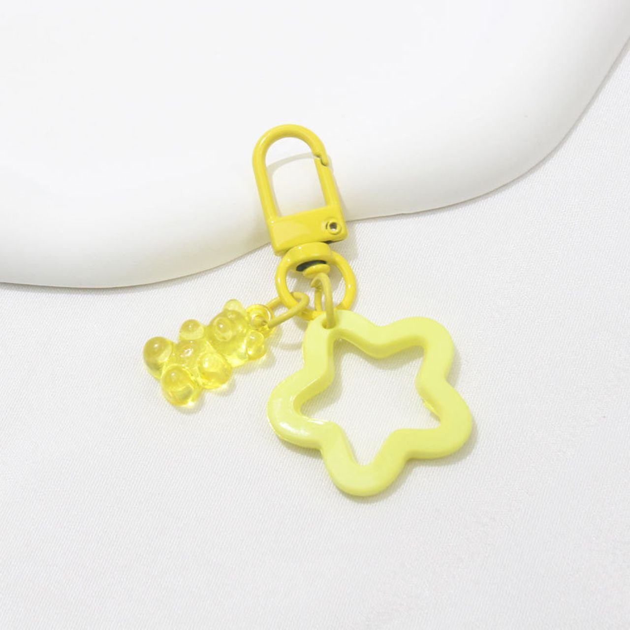 Bright yellow flower and gummy bear keychain on a white surface. Vibrant resin keyring accessory.