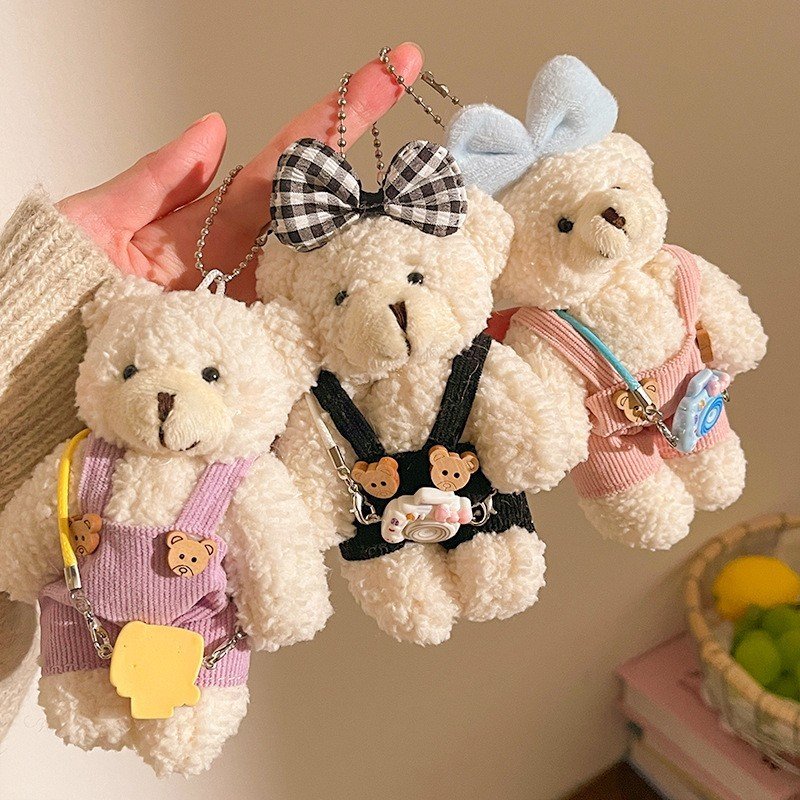 Assorted colors cute teddy bear plush toy keyring holds by a girl in her finger background is colorful