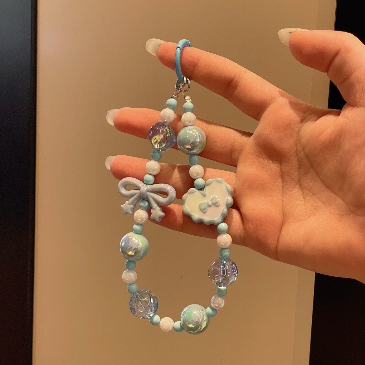 Pastel-colored acrylic beaded mobile phone charm strap with star and heart accents on a while background.