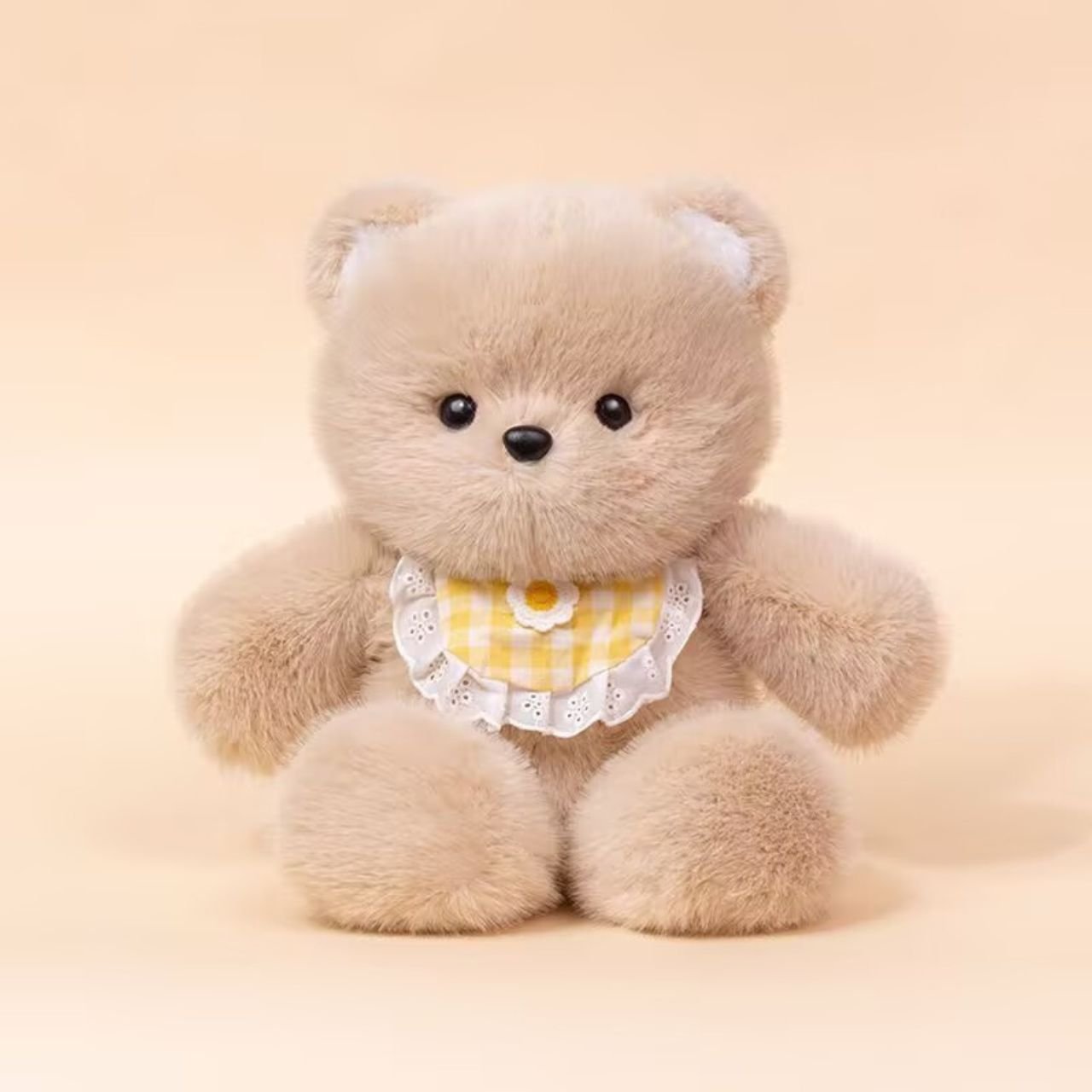 Cute light brown teddy bear plush toy wearing a yellow bib.
